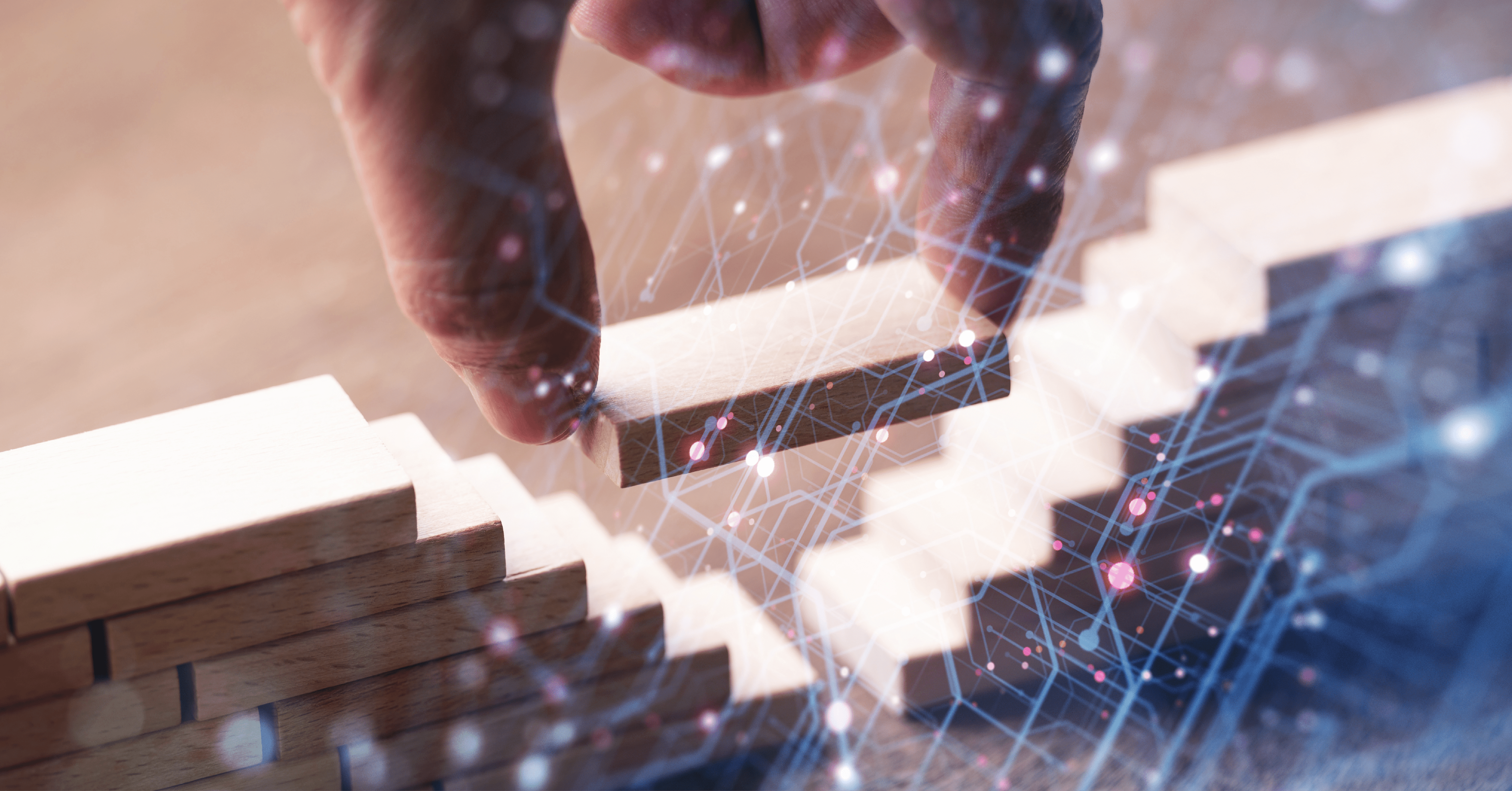 Person placing a wooden building block to bridge the gap between two block structures