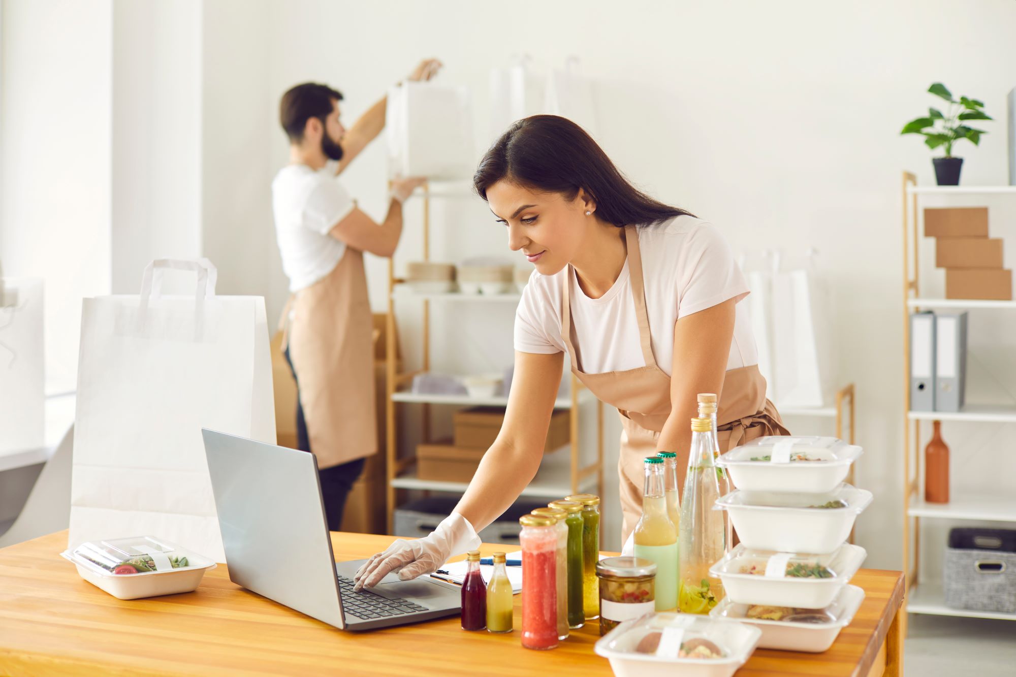 Employees of a food-based business managing orders on shelves and on a laptop